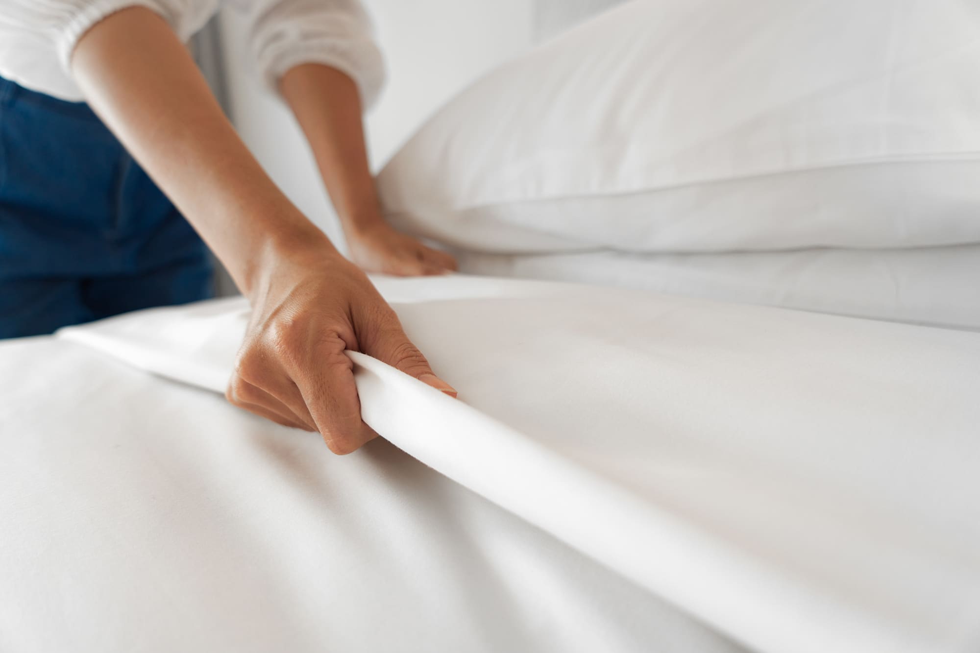 Female Hand set up white bed sheet in bedroom Female Hand set up white bed sheet in bedroom