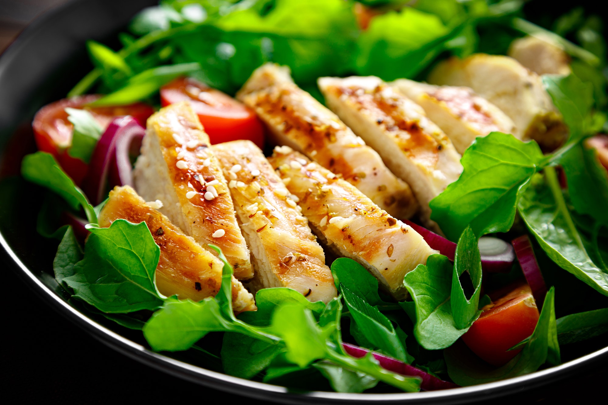 Grilled chicken breast and salad. Fresh vegetable salad with tomato, arugula, spinach and grilled chicken meat in bowl, healthy food. Grilled chicken breast and salad. Fresh vegetable salad with tomato, arugula, spinach and grilled chicken meat in bowl, healthy food.