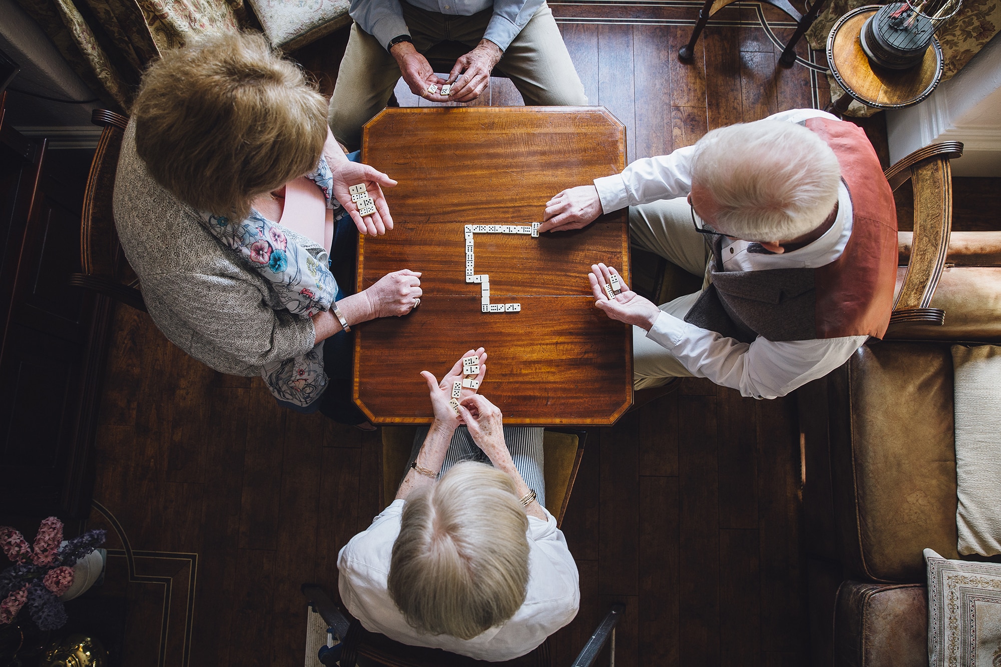 Seniors Playing Dominoes Aerial shot of four senior adults playing dominoes on a table in the nursing home.